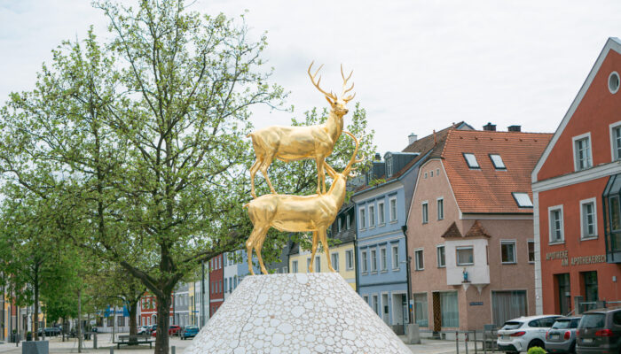 Detailbild des Monte-Hirschau-Brunnens. Der Monte Kaolino wird als kreisrunder Kegel dargestellt. Die vereinzelt eingearbeiteten goldfarbenen Nuggets verweisen auf das „Weiße Gold“ und die „Goldene Straße“. Sie schauen nach Westen und nach Osten und beobachten den Verkehr auf der „Goldenen Straße“.