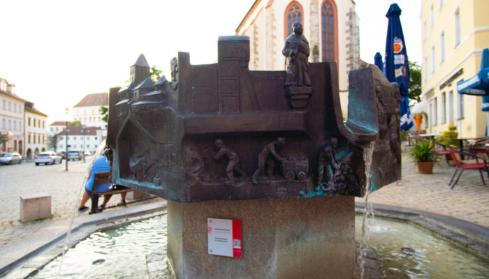 Geschichtsbrunnen vor dem Rathaus Sulzbach-Rosenberg. Der Geschichtsbrunnen in Sulzbach-Rosenberg wurde von dem Etzelwanger Künstler Peter Kuschel 1991 gestaltet und ist ein bedeutendes Wahrzeichen der Stadt und ein beliebter Anziehungspunkt für Touristen und Einheimische gleichermaßen. Vor dem Rathaus gelegen, erzählt der Brunnen die Geschichte der Stadt auf lebendige und sehr lebhafte Weise. Hier können Besucher die Vergangenheit der Stadt hautnah erleben und sich von den vielfältigen Darstellungen und Symbolen inspirieren lassen.