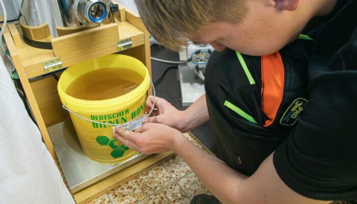 Jungimker Jannik, wie er den Eimer der Honigernte beschriftet