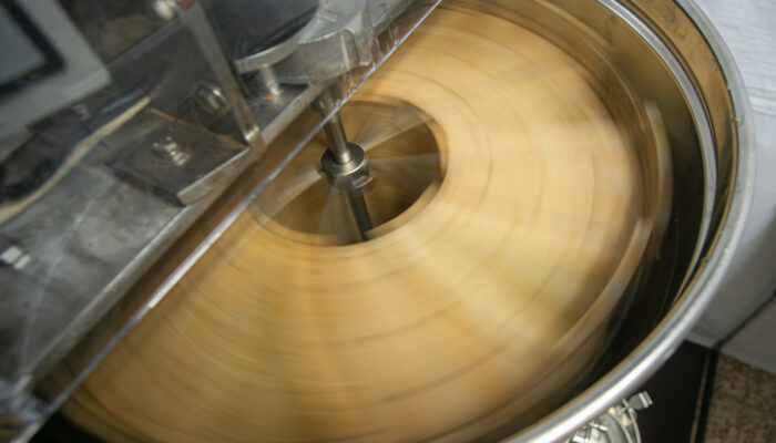 Die Honigschleuder im laufenden Betrieb, durch die schnelle Drehung wird der Honig aus den Waben herausgeschleudert und läuft an der Innenwand herunter.